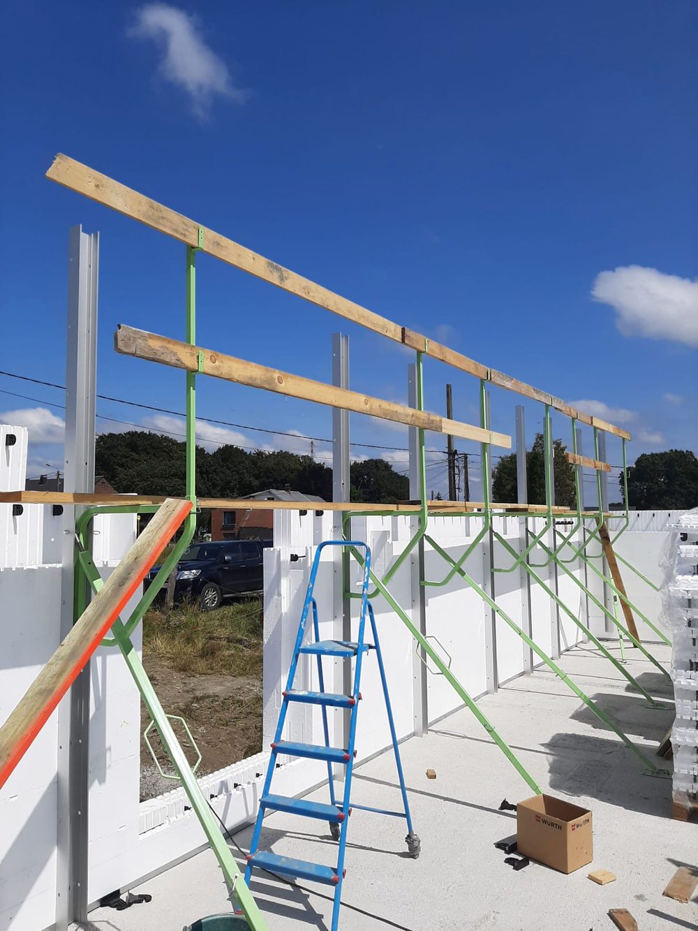ICF bracing system installed on a construction site — green steel braces supporting insulated concrete form walls