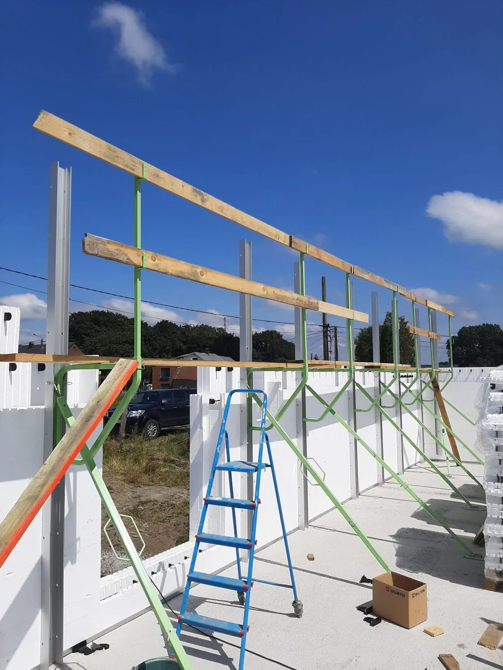 ICF bracing system installed on a construction site — green steel braces supporting insulated concrete form walls